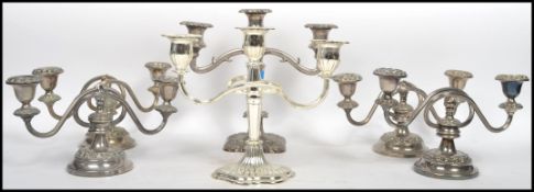 A matching set of four silver plated two arm candelabras / candlesticks raised on stepped circular
