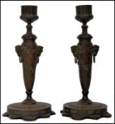 A pair of Victorian Backernalion bronze candle sticks having scalloped bases with tapered column