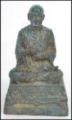 A 19th century Oriental figurine of an elder Buddha moulded in a praying position raised on a square