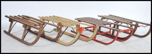 A group of four vintage 20th century children's snow sleighs having bentwood runners with slatted