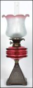 A 19th century bronze and cranberry glass reservoir oil lamp. Triangular terraced base with