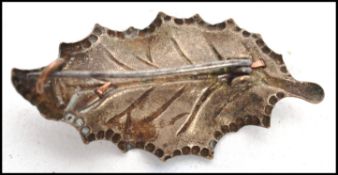 A vintage 20th century sweetheart silver metal brooch in the form of a holly leaf with applied