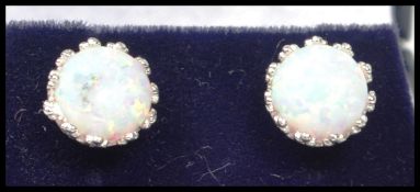 A pair of ladies contemporary 20th century silver and opal stud earrings being claw mounted and