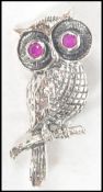 A silver 20th century brooch / pendant in the form of an owl inset with ruby stone eyes