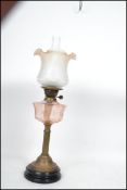 An early 20th Century oil lamp having a flute and tulip style shade raised above a faceted reservoir