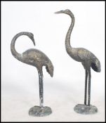 A pair of decorative 20th century cast brass garden ornaments, each in the form of asiatic cranes.