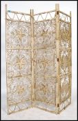 A 20th century three panel folding screen of rattan wicker construction having a pierced floral