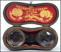A pair of early 20th century brass opera glasses by Negretti & Zambra, having faceted leather