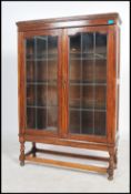 A 1930's oak two door display cabinet, the two lead glazed doors enclosing three adjustable shelves,