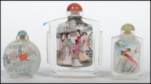 A group of three Chinese glass scent bottles each with applied decorated panels of court scenes
