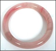 A vintage oriental carved pink jade bangle of circular form.