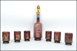 A 20th century studio art cranberry glass decanter and drinking glass set by Murano consisting of