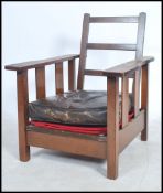A 1930's Art Deco oak fireside reclining armchair having slatted back with loose cushion to the