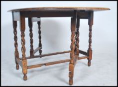 A 1920's good quality oak barleytwist drop leaf dining table being raised on barley twist legs