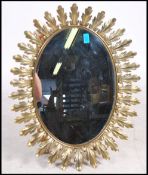 A vintage 20th century French oval glass mirror having a sunburst acanthus leaf mount. Measures