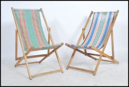 A pair of mid century deck chairs with wooden frames and a striped material hammock.