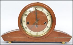 A vintage art deco style wooden cased mantle clock by Bentima having an circular face with sloped