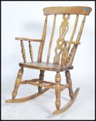 A 20th Century elm and beech child's Windsor rocking chair With a concave top rail above a pierced