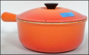 A 20th century Le Crueset lidded saucepan in orange colourway. Marked to base, complete with the