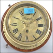 A early 20th century brass bulkhead nautical ships clock having a roman numeral chapter ring,
