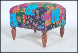 A vintage 20th century large cube footstool raised on four carved legs with a floral patchwork