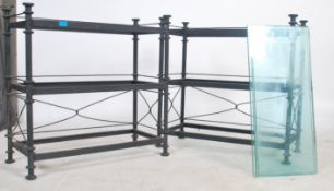 A pair of matching heavy cast three tier iron ebonised iron and glass display units.
