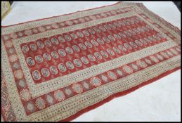 A large early 20th century Persian floor rug of red ground having a central panel surrounded by