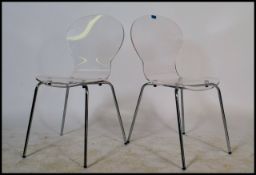 Pair of retro dining chairs having clear plastic seats raised on tubular chrome legs inspired by
