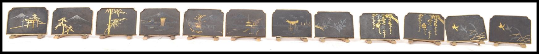 A collection of twelve mid 20th century gold plated Japanese place setting name holders, each with a