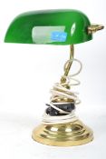 A vintage 20th century bankers desk lamp having an adjustable green glass shade raised on a brass