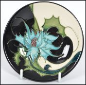 A Moorcroft ceramic tube lined coaster pin dish decorated in the Sea Holly pattern complete in the