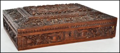 A 19th century camphorwood jewellery box of sarcophagus form intricately carved with panels