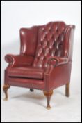 A 20th antique style Oxblood leather wing backed Chesterfield armchair with button back detailing
