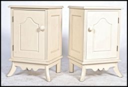 A pair of painted off white / cream bedside cabinets having open recess above swing door with turned