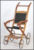 A Victorian walnut upholstered disability push chair - wheel chair. The walnut frame with green