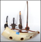 A collection of 4 vintage 20th century smoking pipes together with a hanging ox horn pipe holder.