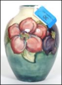 A c1950s Walter Moorcroft globular vase having tube lined and painted floral decoration on a blue