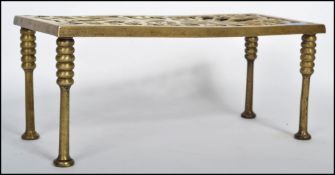 A 19th century brass fireside trivet of rectangular form having a fret pierces design atop raised on