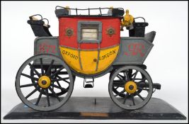 A vintage style model of a London English Mail Coach, in yellow colourway on a plinth base with