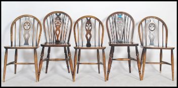 A set of 4 20th century country oak wheelback dining chairs being raised on turned legs united by