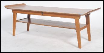 A retro 20th century 1970's teak wood surfboard style coffee table being raised on squared