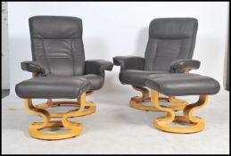 A pair of black leather Ekornes Stressless style reclining armchairs being upholstered in black