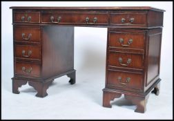 A Georgian style twin pedestal desk having green leather top with three drawers to each pedestal