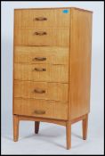 A retro 1970's upright natural oak pedestal chest of drawers being raised on tapering legs with an