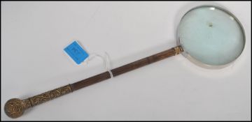 A stunning bamboo and ormolu handled hand held magnifying glass, the shaft decorated with chase