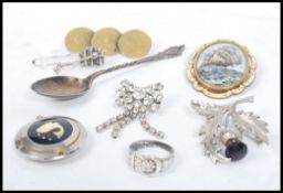 A collection of silver costume jewellery to include a silver ring in the form of a belt, brooches,