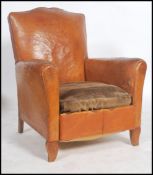 A 1930's Art Deco tan full grain leather moustache back French club armchair having barrel arms