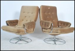 A pair of retro 20th century button back upholstered wing back style swivel armchairs raised on