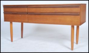 A 1960's teak four drawer sideboard comprising of two short and two long raised on shaped legs in