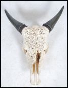 An Indian / Persian caved cow skull and horns, having stunning fret pierced decoration to the